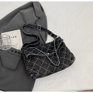 Dettaglio borsa a tracolla in denim grigio scuro con cuciture a rombi e catena metallica