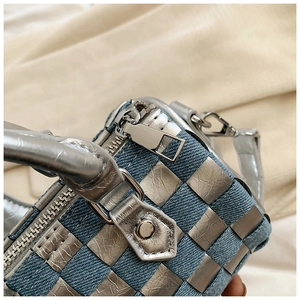 Detailed close-up of blue denim and silver metallic woven fabric with chrome zipper