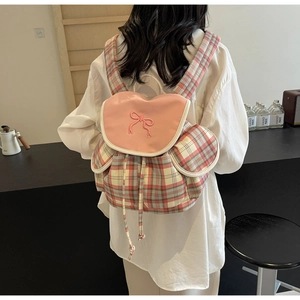 Détail du sac à dos à carreaux roses avec rabat en cuir et nœud papillon brodé