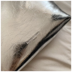 Détail macro du sac à main argenté métallisé avec logo embossé et cuir froissé
