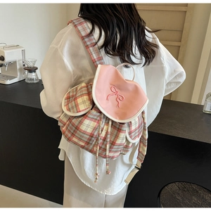 Jeune femme portant un sac à dos à carreaux roses avec broderie nœud dans un café