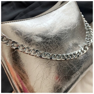 Détail de la chaîne argentée sur sac en similicuir métallisé avec logo gaufré chic