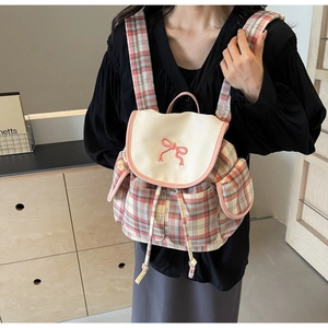 Détail de la fermeture à cordon et du nœud rose sur ce sac à dos à carreaux