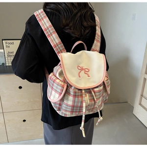 Détail d'un sac à dos à carreaux roses avec un nœud décoratif et fermeture à cordon