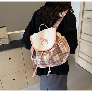 Détail du sac à dos à carreaux avec broderie nœud rose et rabat en similicuir blanc