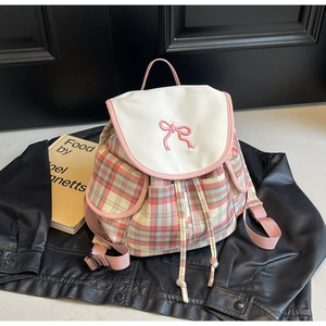 Détail d'un sac à dos à carreaux roses avec broderie nœud et fermeture à cordon sur fond noir