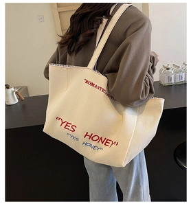 Detailed view of spacious canvas tote bag featuring red Yes Honey embroidery details
