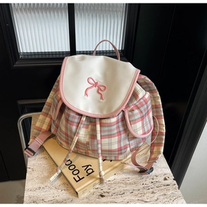 Vue détaillée d'un sac à dos à carreaux avec broderie de nœud rose et cordon de serrage