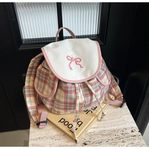Détail d'un sac à dos à carreaux avec broderie de nœud rose et poches à rabat classiques