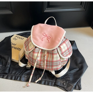 Détail du sac à dos à carreaux roses avec nœud brodé et cordon de serrage sur cuir noir