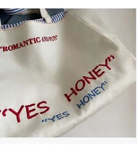Detail of canvas tote bag with 'Romantic and Fun' embroidery and blue striped lining