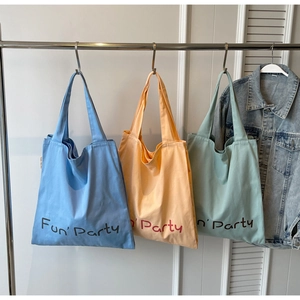 Détail de sacs cabas en toile bleu, jaune et vert avec impression Fun Party