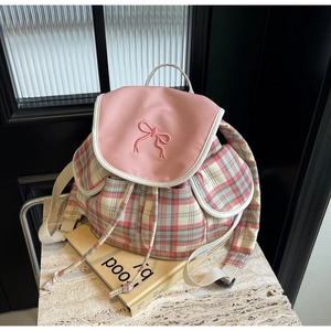 Détail de la broderie de nœud rose et du motif à carreaux sur le rabat d'un sac à dos