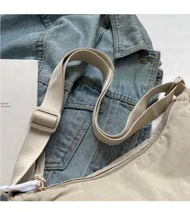 Detail of adjustable wide shoulder strap and nylon fabric on beige crossbody bag