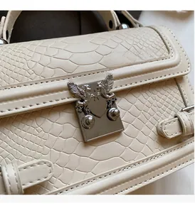 Close-up of cream crocodile pattern leather with silver horse-shaped metal buckle