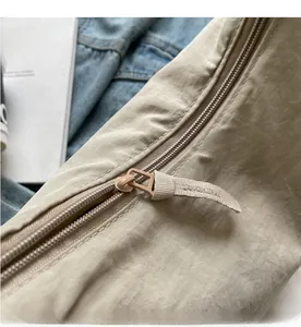 Detailed macro view of smooth color-matched zipper on a nylon crossbody dumpling bag