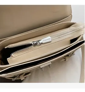 Detailed close-up of smooth metal zipper and internal compartments of cream leather bag