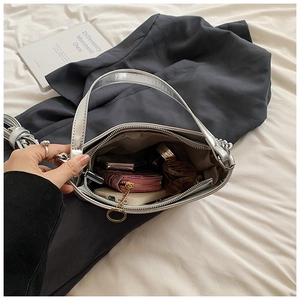 Sac à main argenté brillant montrant un intérieur spacieux pour essentiels et zip
