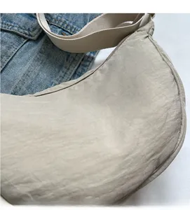 Detail of the soft beige fabric texture and smooth zipper on the crescent crossbody bag