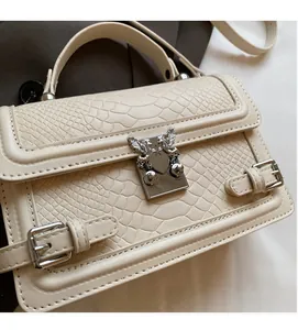 Detail of cream faux crocodile leather handbag with silver shield lock and buckle