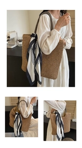 Detail of hand-woven straw tote with black and white striped handle and silk scarf