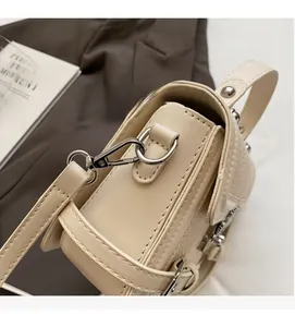 Close-up of polished silver hardware and leather texture on a beige crossbody bag