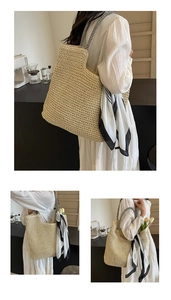 Close-up of large woven straw tote bag featuring striped handles and geometric scarf detail
