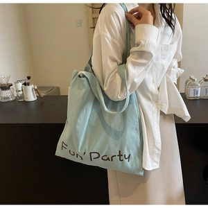 Détail du sac fourre-tout bleu clair en toile avec imprimé Fun Party dans un café