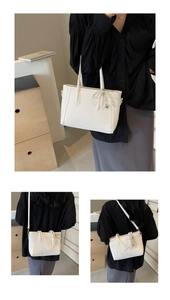 Detail of white lychee leather tote bag featuring a pearl bow charm and crossbody strap