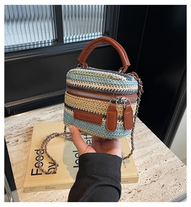 Detail of multi-color woven straw mini bag with metal zipper and brown leather handle