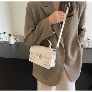 Detail of cream crossbody bag featuring faux crocodile texture and silver hardware