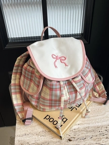 Sac à dos à carreaux rose et bleu avec broderie nœud sur une table en pierre