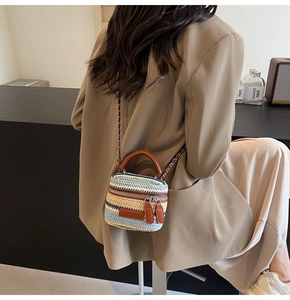 Close-up of a striped handmade woven mini bag with metal chain strap worn by a model