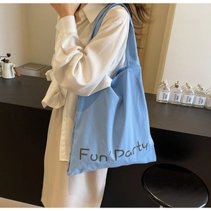 Gros plan du sac fourre-tout en toile bleu clair avec l'imprimé Fun' Party au café