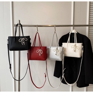 Detail of four stylish tote bags in black, red, silver, and white with pearl bow charms