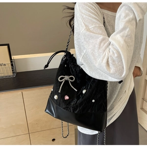 Detail of black velvet bucket bag featuring diamond bow and pearl heart charms