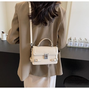 Model wearing a cream-colored crocodile embossed crossbody bag with butterfly clasp