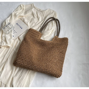 Detail of a brown woven tote bag with striped handles on a white summer dress