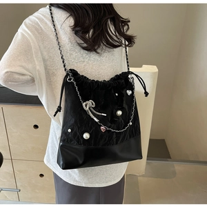 Detail of black drawstring bucket bag with pearls, silver chains, and metal charms