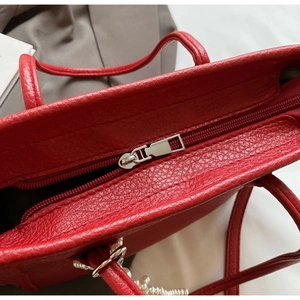 Close-up of red lychee texture leather tote with metallic zipper and pearl chain detail