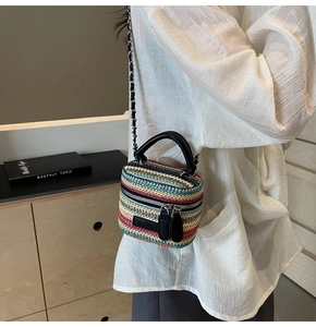 Detail view of multi-color woven straw crossbody bag with metal chain strap