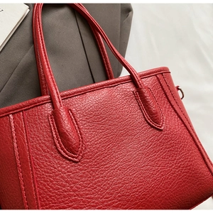 Detailed macro view of red lychee grain leather tote bag with reinforced double handles