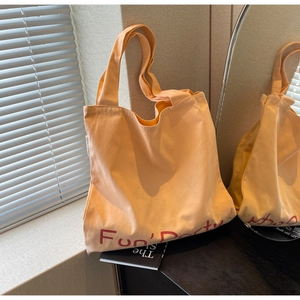 Gros plan du sac cabas en toile orange clair avec texte Fun Party rouge sur une table