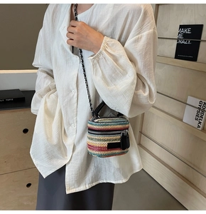 Detail of colorful striped mini straw bucket bag with leather chain strap and zipper