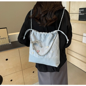 Detail of light blue bucket bag with rhinestone bow, pearls, and silver chain strap