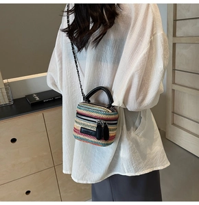 Detail of colorful woven straw bag with contrast stripes and silver chain strap