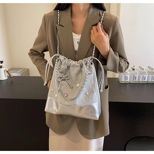 Detailed view of silver bucket bag with pearl chain and pink heart pendant