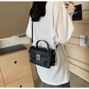 Detail of black snakeskin texture crossbody bag with silver hardware on a female model