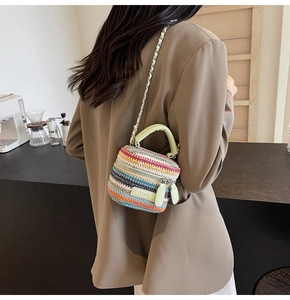 Detailed view of mini woven straw bucket bag with green leather trim and chain strap