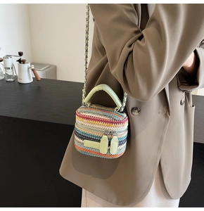 Detail of multi-color woven straw crossbody bag with green leather handle and gold chain strap